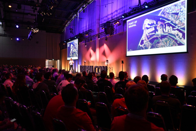 Dries Buytaert steht auf der Bühne der DrupalCon Rotterdam, hinter ihm eine große Leinwand mit der Folie "Port of Drupal" und den Begriffen Drupal AI, Canvas, Site Templates und Recipes